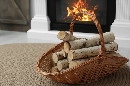 Firewood in wicker basket near fireplace indoorsの写真素材