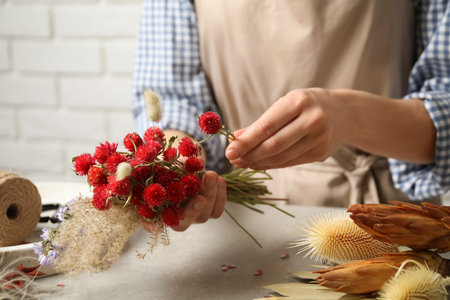 Florist making bouquet of dried flowers at light gray table, closeupの写真素材