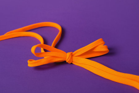 Orange shoe laces tied in bow on purple backgroundの写真素材