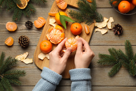 Woman peeling fresh tangerine on wooden table, top view. christmas atmosphereの写真素材