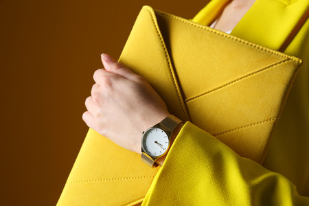 Woman wearing luxury wristwatch on brown background, closeupの写真素材