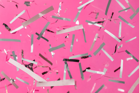 Shiny silver confetti falling down on pink backgroundの写真素材