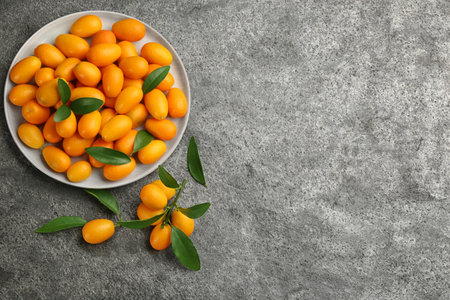 Fresh ripe kumquats on gray table, flat lay. Space for textの写真素材