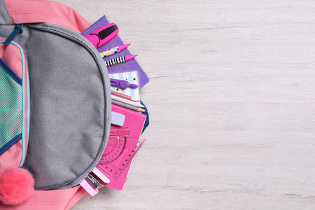 Backpack with different school stationery on wooden table, top view. Space for textの写真素材