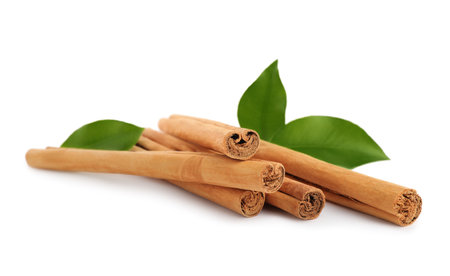 Aromatic dry cinnamon sticks and green leaves on white backgroundの写真素材