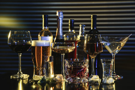 Many different alcoholic drinks on table against dark background