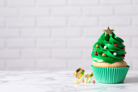 Christmas tree shaped cupcake on white marble table. Space for textの写真素材