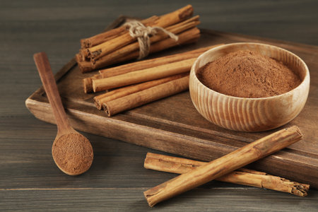 Aromatic cinnamon sticks and powder on wooden tableの写真素材
