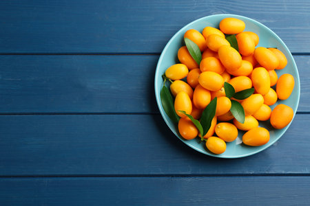 Fresh ripe kumquats on blue wooden table, top view. Space for textの写真素材