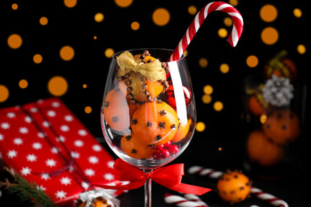 Christmas composition with tangerine pomander balls in wineglass against blurred lightsの写真素材