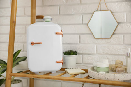 Mini fridge for cosmetic products on shelf near white brick wallの写真素材