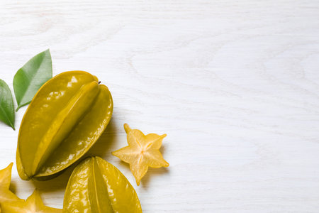 Delicious carambola fruits on white wooden table, flat lay. Space for textの写真素材