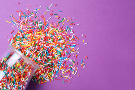 Jar with colorful sprinkles and space for text on purple background, flat lay. Confectionery decorの写真素材