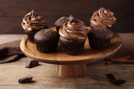 Delicious chocolate muffins and cupcakes decorated with cream on wooden tableの写真素材
