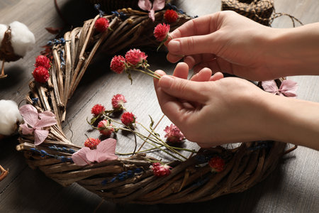 Florist making wreath with dried flowers on wooden table, closeupの写真素材