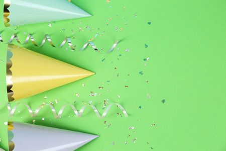 Bright party hats, serpentine streamers and confetti on green background, flat layの写真素材
