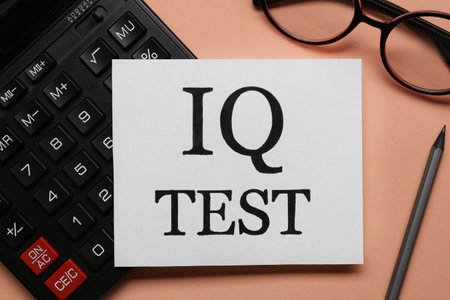 Note with text IQ Test, calculator, glasses and pencil on coral background, flat layの写真素材