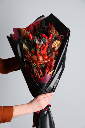 Woman with beautiful food bouquet on light gray background, closeupの写真素材