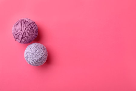 Soft colorful woolen yarns on pink background, flat lay. Space for textの写真素材