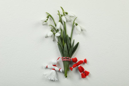 Beautiful snowdrops with traditional martisor on white background, flat lay. Symbol of first spring dayの写真素材