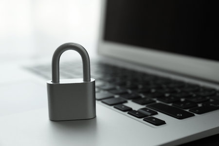 Metal lock and laptop on light background, closeup. cyber security conceptの写真素材
