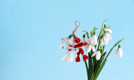 Traditional martisor and beautiful snowdrops on light blue background, space for text. Symbol of first spring dayの写真素材