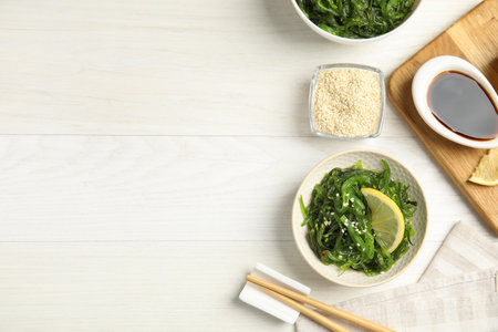 Japanese seaweed salad with lemon slice served on white wooden table, flat lay. Space for textの写真素材