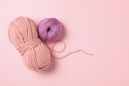 Soft woolen yarns on pink background, flat lay. Space for textの写真素材