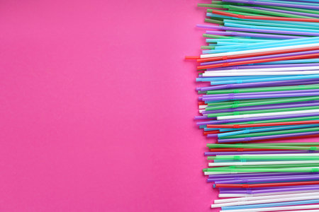 Colorful plastic drinking straws on pink background, flat lay. Space for textの写真素材