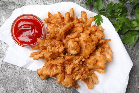 Fried blooming onion with dipping sauce served on gray table, flat layの写真素材