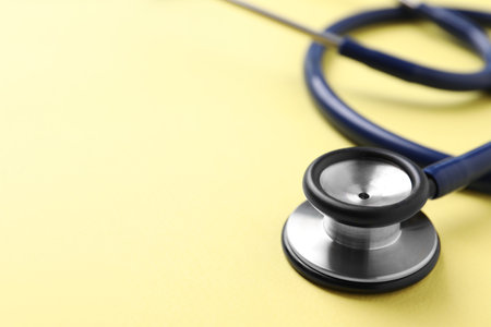 Stethoscope on yellow background, closeup. Space for textの写真素材