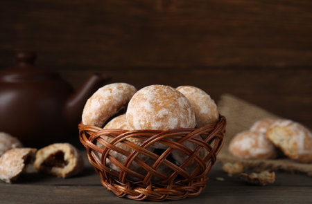 Tasty homemade gingerbread cookies in wicker basket on wooden tableの写真素材