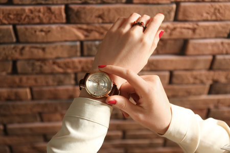 Woman wearing luxury wristwatch near brick wall, closeupの写真素材