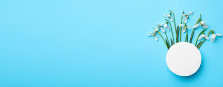 Beautiful snowdrops and paper card on light blue background, flat lay. Space for textの写真素材