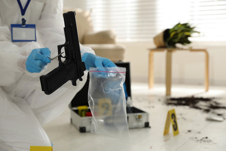 Investigator in protective suit working at crime scene indoors, closeup