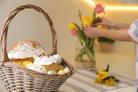Basket with traditional Easter cakes and dyed eggs on table indoors, space for textの写真素材