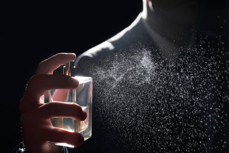 Man spraying luxury perfume on black background, closeupの写真素材