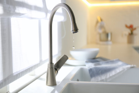 Water drops falling down from tap in kitchen