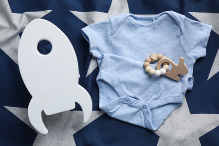 Rocket shaped child's night lamp, baby bodysuit and rattle on color fabric, flat layの写真素材