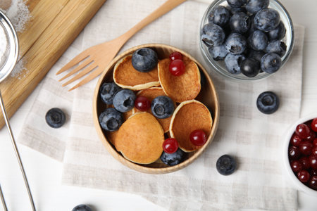 Delicious mini pancakes cereal with berries served on white table, flat layの写真素材