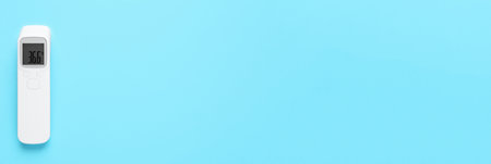 Infrared thermometer on light blue background, top view with space for text. Checking temperature during Covid-19 pandemicの写真素材