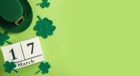 Leprechaun's hat, block calendar and St. Patrick's day decor on green background, flat lay. Space...