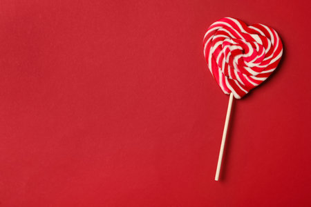 Sweet heart shaped lollipop on red background, top view with space for text. Valentine's day celebrationの写真素材