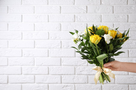 Woman with bouquet of beautiful peony tulips near white brick wall, closeup. Space for textの写真素材