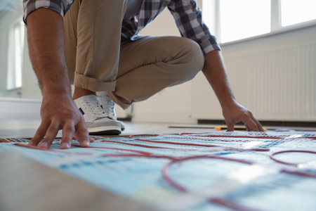Professional worker installing electric underfloor heating system indoors, closeupの写真素材