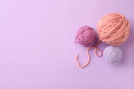 Soft colorful woolen yarns on lilac background, flat lay. Space for textの写真素材