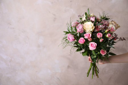 Woman with bouquet of beautiful roses on beige background, closeup. Space for textの写真素材