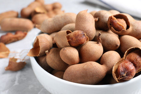 Delicious ripe tamarinds in ceramic bowl on table, closeupの写真素材