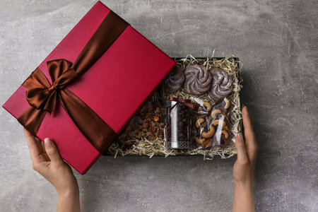 Woman with gift box of chocolate and sweets at light gray table, closeupの写真素材