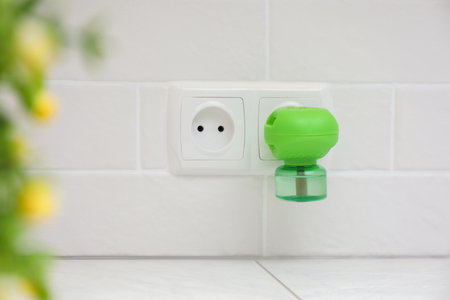 Electric vaporizer with insect repellent liquid plugged in socket at homeの写真素材